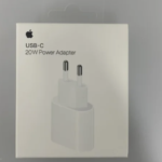 En vit låda märkt "iPhone 20 Watts Laddare" med Apple-logotypen visar en vit USB-C väggladdare med två runda stift.